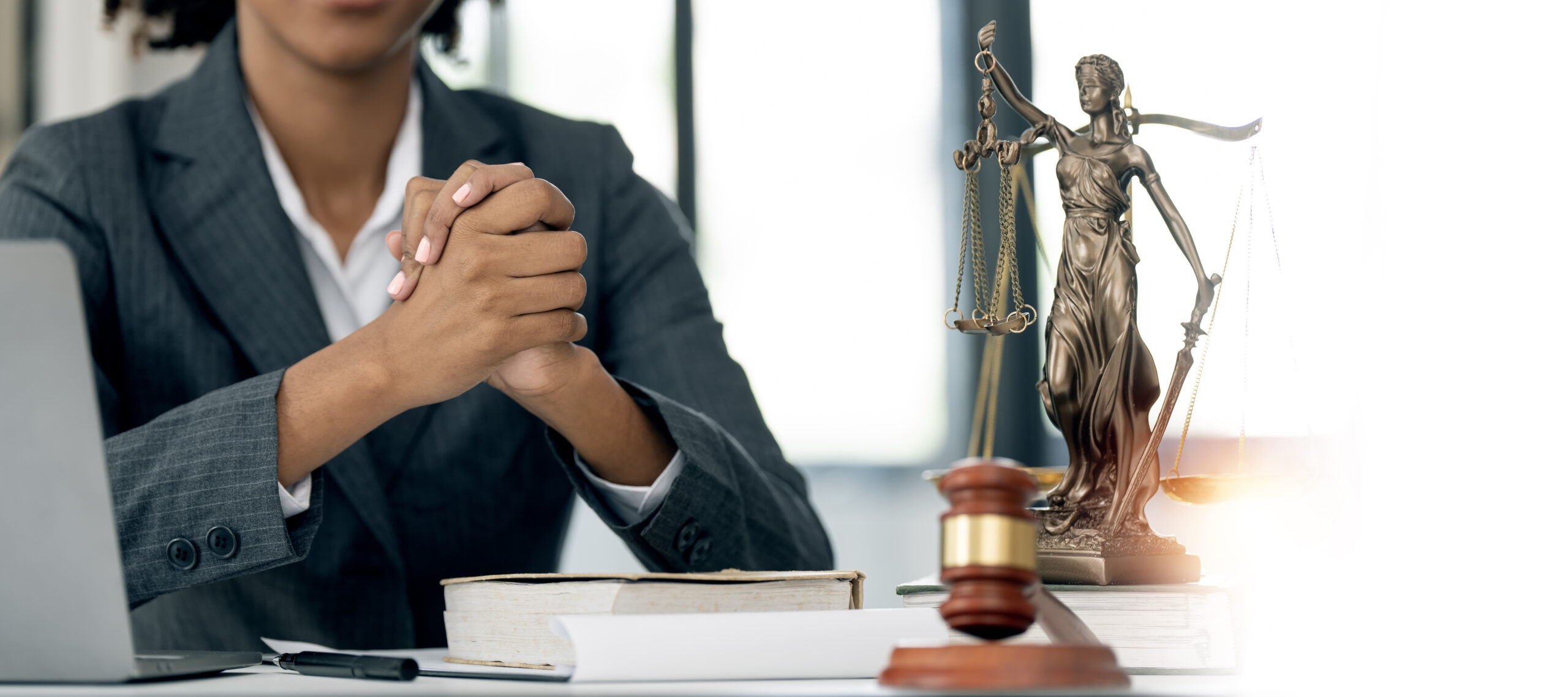 Female justice lawyer holding her hands together sitting at desk