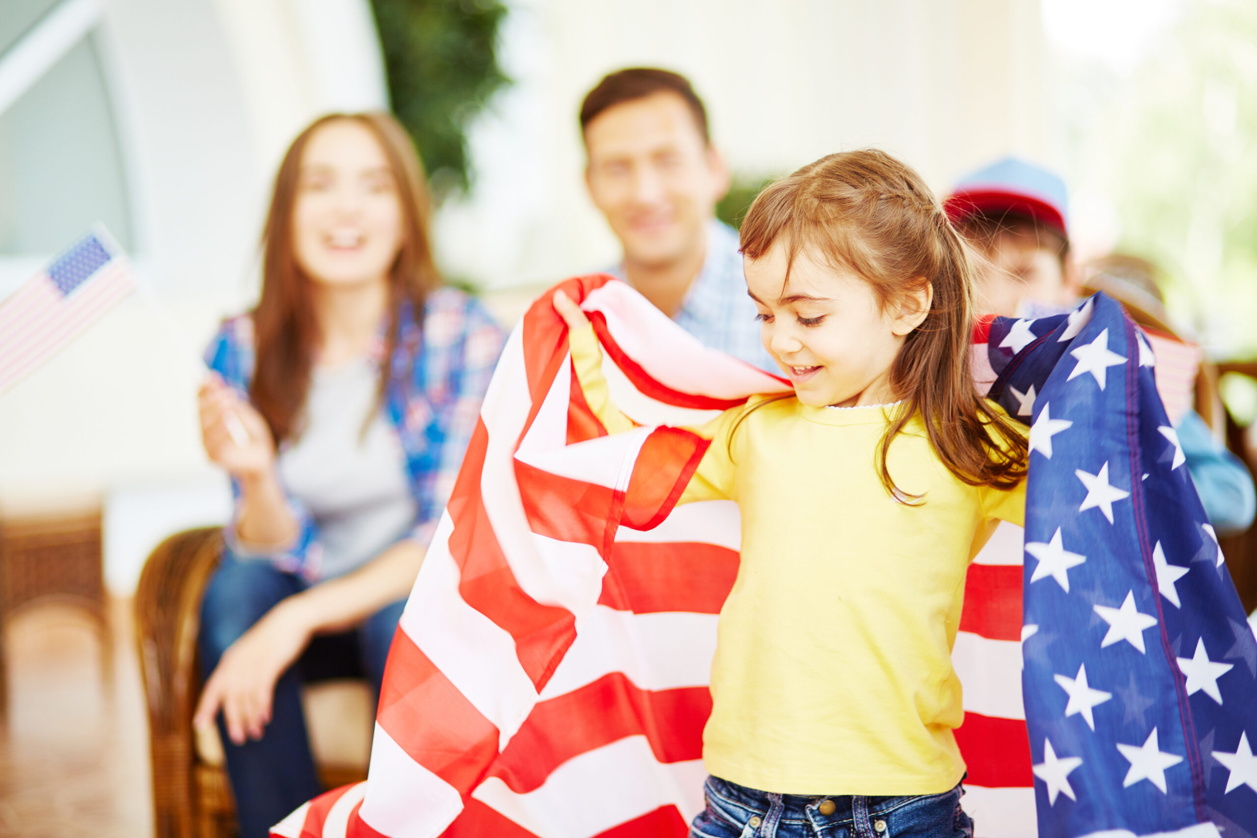 Adorable girl wrapping herself in USA flag