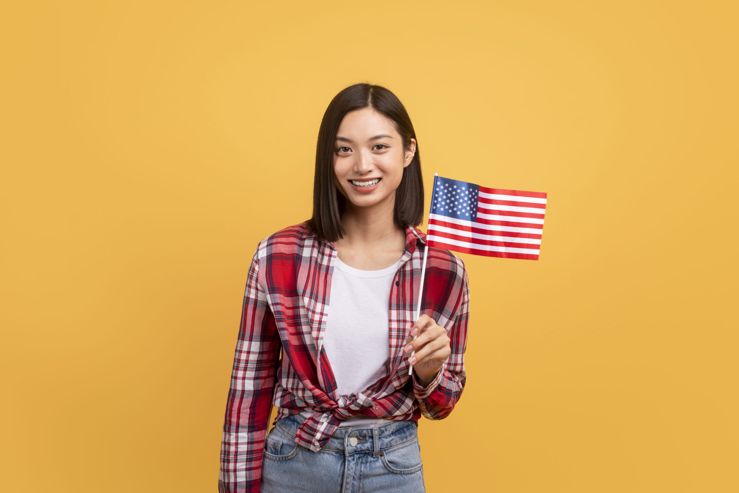 Education abroad, studying in the US, emigration concept. Happy asian female student holding american flag